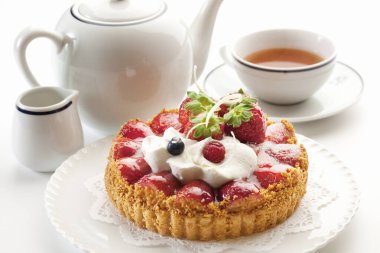 Çilekli lezzetli tart ve arka planda çay, yakın plan.