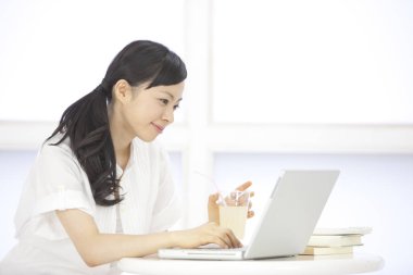 İç mekanda dizüstü bilgisayarla çalışan Asyalı güzel bir kadının portresi.