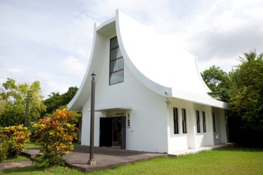 Çevresi yeşil ağaçlarla çevrili modern beyaz kilise binası