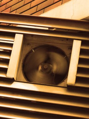Dış binadaki metal çatalların arkasında dönen endüstriyel havalandırma vantilatörü.