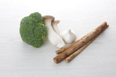 Taze çiğ brokoli, sarımsak, mantar ve beyaz arka planda Burdock kökü.