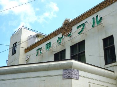 Mavi gökyüzünün altında Japon tabelası bulunan tarihi beyaz bina. 