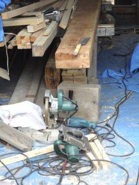 Yığılmış ahşap kirişler elektrik aletleri ve kabloların yanında duruyor.