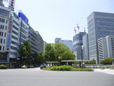 Geniş boş caddeyi çevreleyen yüksek binaların yer aldığı modern şehir manzarası