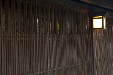 Ahşap bambu çit. Akşam ışığında parlayan fener var.