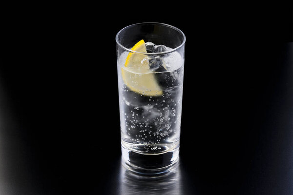 стакан джина и тоника со льдом и лимоном на темном фоне