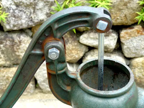 Dışarıya temiz su döken eski metal su pompası.