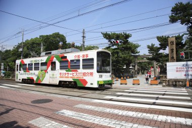 Aerodinamik tramvay Japonya 'daki işlek şehir caddesinden geçen raylar boyunca süzülüyor..