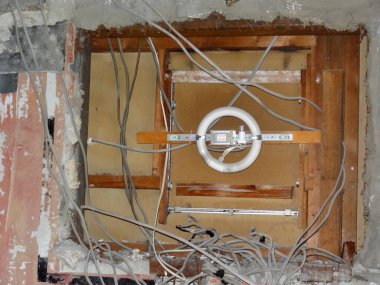 Dairesel floresan lamba armatürünü çevreleyen açığa çıkmış elektrik kabloları