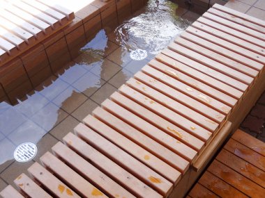 Sığ fayanslı su havuzunu çevreleyen ahşap banklar.