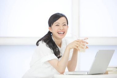 İç mekanda dizüstü bilgisayarla çalışan Asyalı güzel bir kadının portresi.