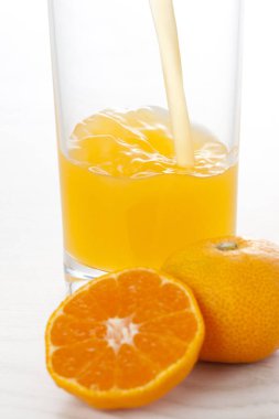 Bardakta sağlıklı meyve suyu ve taze mandalina.