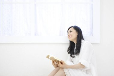 Evdeki kanepede kitap okuyan kadın.