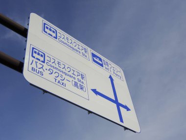 Açık gökyüzünün altında yön gösteren mavi Japon yol tabelası