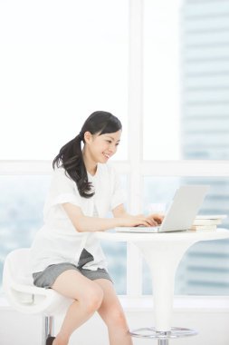 Evde gülümseyen ve dizüstü bilgisayar kullanan güzel bir kadının portresi.