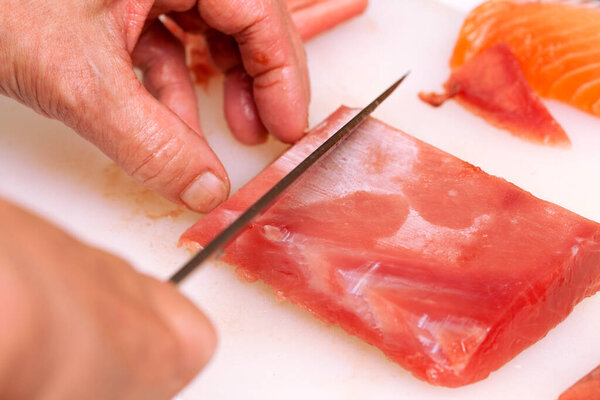 человек режет сырого лосося на деревянном столе