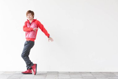 Genç Asyalı adam kırmızı ceketli ve siyah pantolonlu beyaz arka planda poz veriyor. 