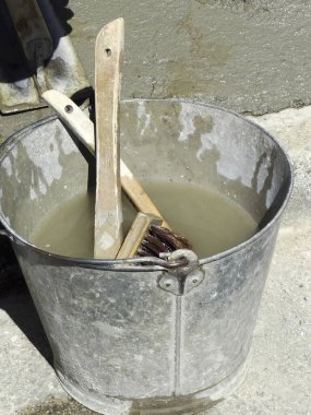 Boya fırçalarını bulanık suda tutan metal bir kova.