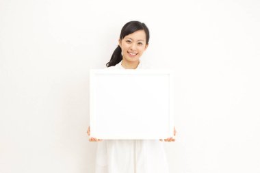 Güzel Asyalı genç bir kadının portresi açık renkli bir iç mekânda boş afiş taşıyor.