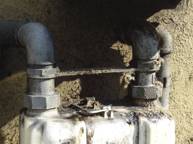 Eski yıpranmış yüzeye bağlı paslı metal borular görünüyor.