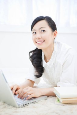 Dizüstü bilgisayar üzerinde çalışan Asyalı kadın gülümseyerek