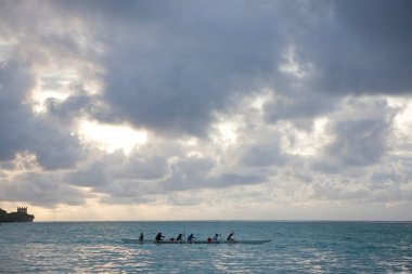 Günbatımında kano teknesine binen turistler 