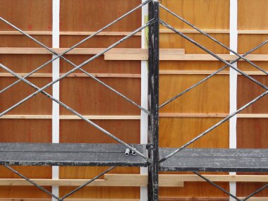 Ahşap inşaat duvarına karşı metal iskele geçişi