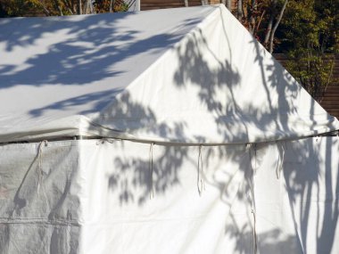 Ormandaki bir kamp alanındaki beyaz çadırda gölgeler.