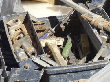 Eski siyah alet çantasının içine saçılmış paslı el aletleri.