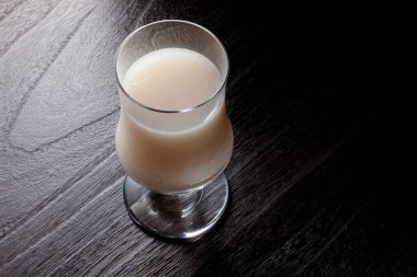 Ahşap masa arkasında beyaz kokteyl içeceği.          