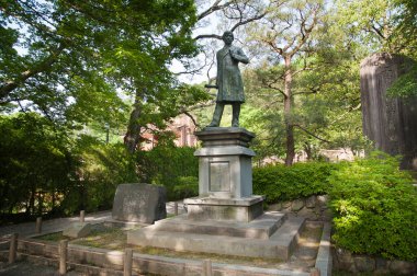 Yıpranmış Japon heykeli bu görkemli yaz akşamında sessiz bir yansıma sunuyor..