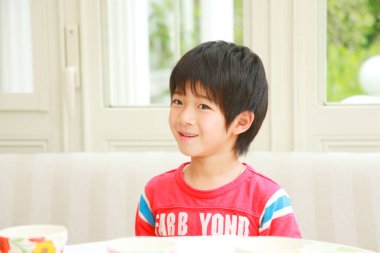 Masanın yanındaki mutlu Asyalı çocuk.