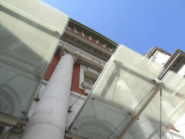 Cam paneller ve sütunlardan tarihi binaya doğru bakıyor