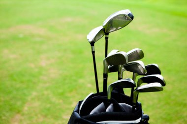 Golf sahasının yeşil çimlerine karşı çantada golf sopaları