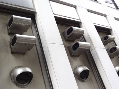 Endüstriyel metal menfezlerin modern bina cephesinden çıktığını gösteren açılı bir bakış açısı