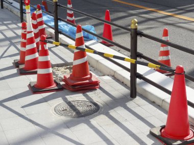 Caddenin yakınındaki hasarlı kaldırımı çevreleyen turuncu trafik konileri