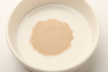 Scattered dry yeast in white bowl