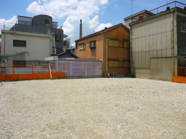 Mavi gökyüzünün altındaki binalarla çevrili boş çakıllar.