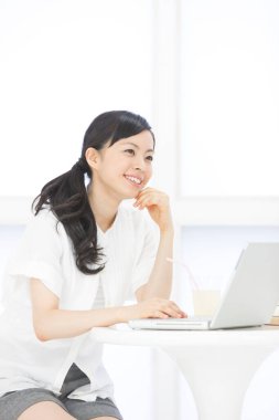 İç mekanda dizüstü bilgisayarla çalışan Asyalı güzel bir kadının portresi.