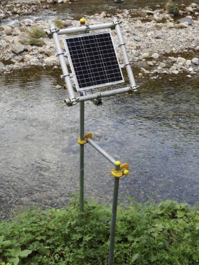 Nehrin kenarına yeşil bitkilerle çevrili güneş paneli yerleştirildi