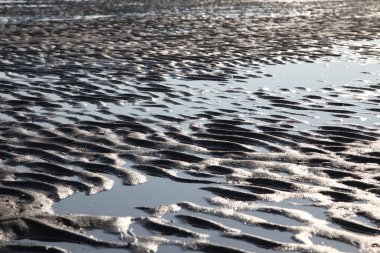 Güneşli bir akşamda kumsalda deniz suyu ve kum