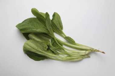Beyaz arka planda taze yeşil yapraklı sebzeler.