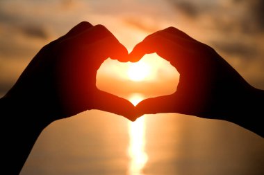 Gün batımına karşı kalp şeklinde eller