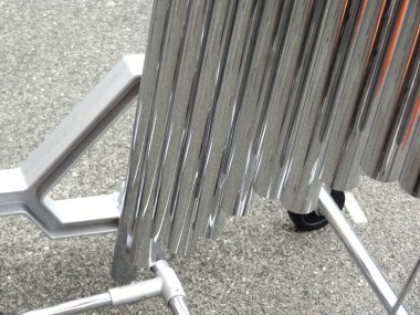 Güneş ışığını yansıtan parlak metal borular desenli asfalt yüzeyinde