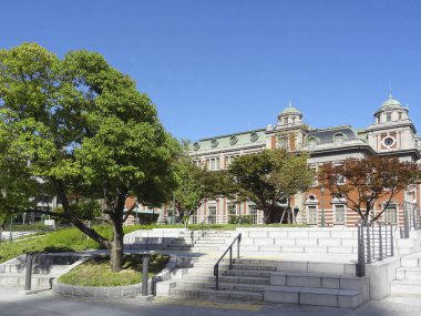 Gökyüzünün altındaki yeşil ağaçların yanındaki tarihi tuğla bina