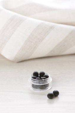 Çizgili kumaşın yanında duran küçük siyah boncuklar.