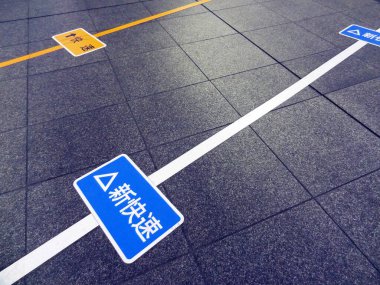 Mavi uyarı işaretleri gri döşemede yatıyor.