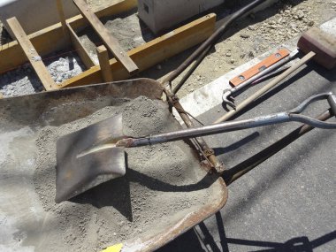 Kürek dışarıda kuru betonla dolu el arabasının içinde dinleniyor.