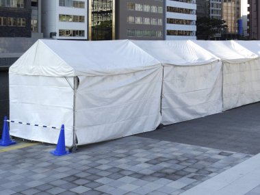 Modern şehir kaldırımlarını kaplayan beyaz çadırlar.