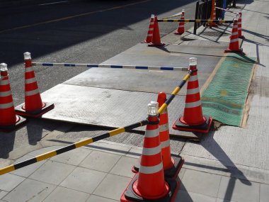 Kaldırımdaki inşaat alanını çevreleyen turuncu trafik konileri